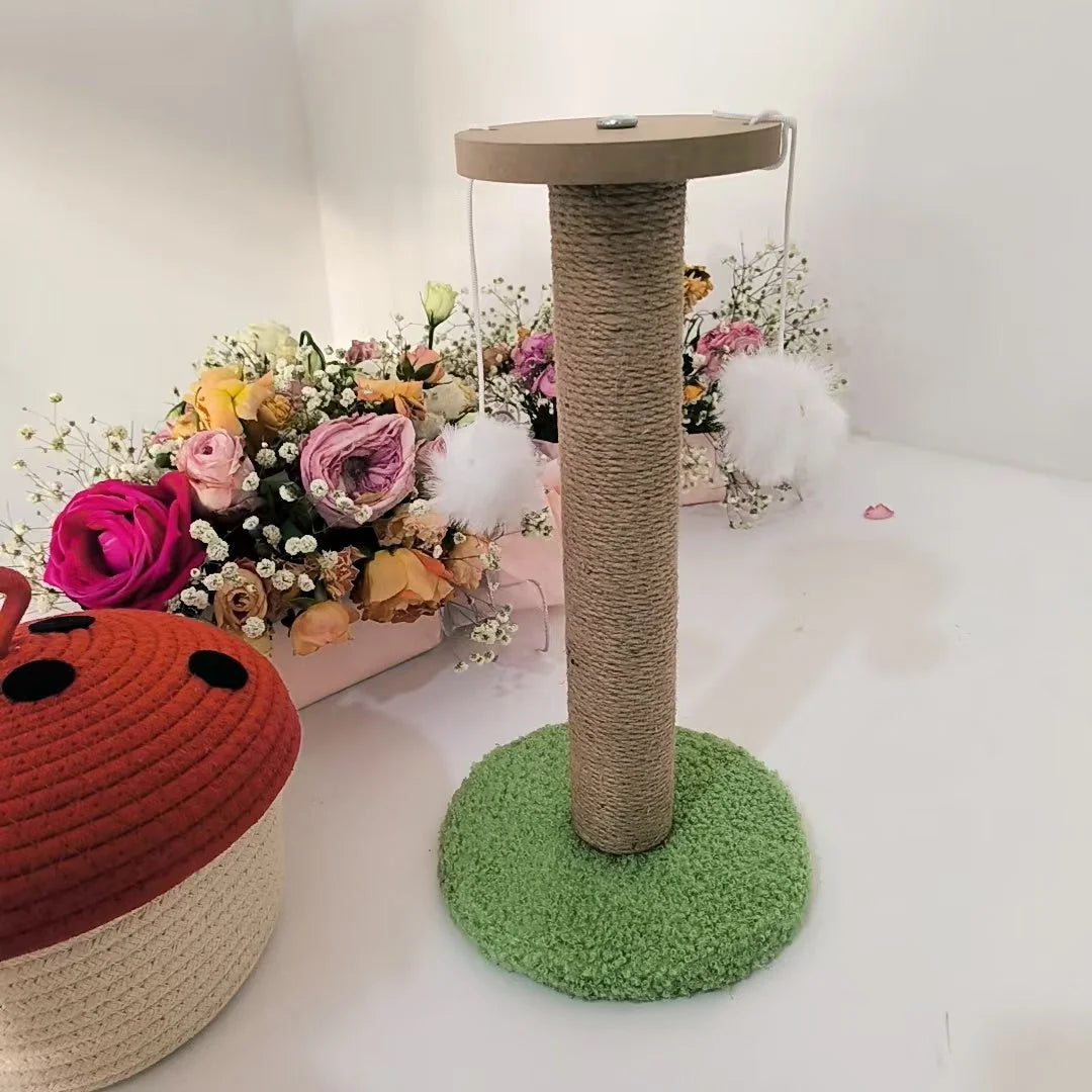 Side view of an assembled cat condo scratching post standing tall, with fluffy hanging toys and floral arrangements in the background.
