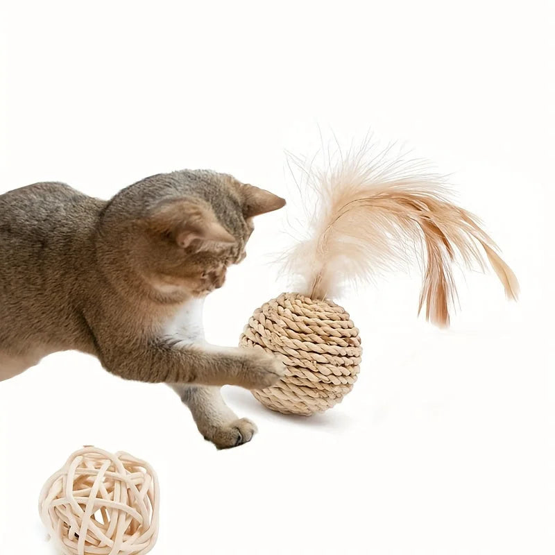 A cat playing with a woven cat scratch ball toy that has a feather and built-in bell making play.