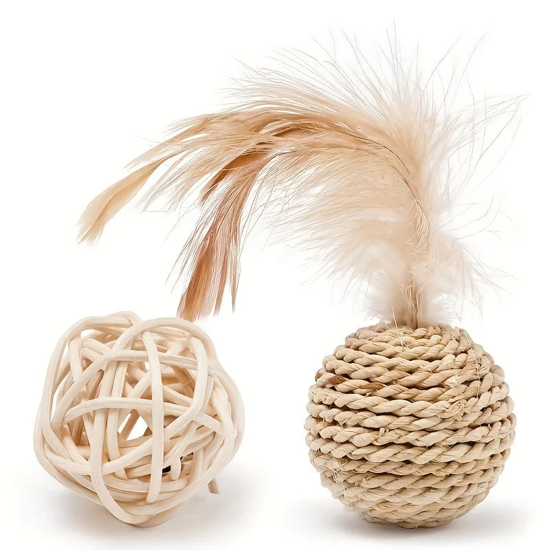 A cat playing with a woven cat scratch ball toy with a feather on top, alongside a rubber ball.