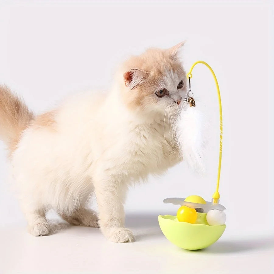 A fluffy white feather attached to a yellow cat toy feather wand, with a cat curiously exploring it.