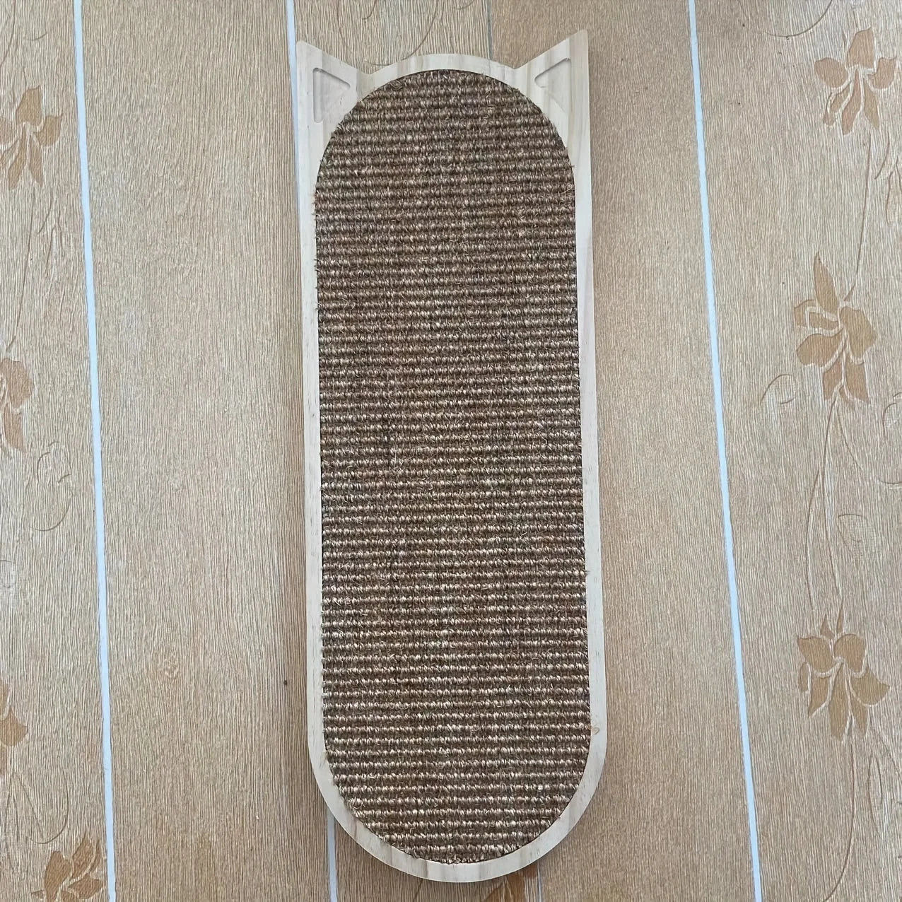 Front view of a cat wall scratching post with natural sisal material and cat-shaped wooden frame placed on the floor.
