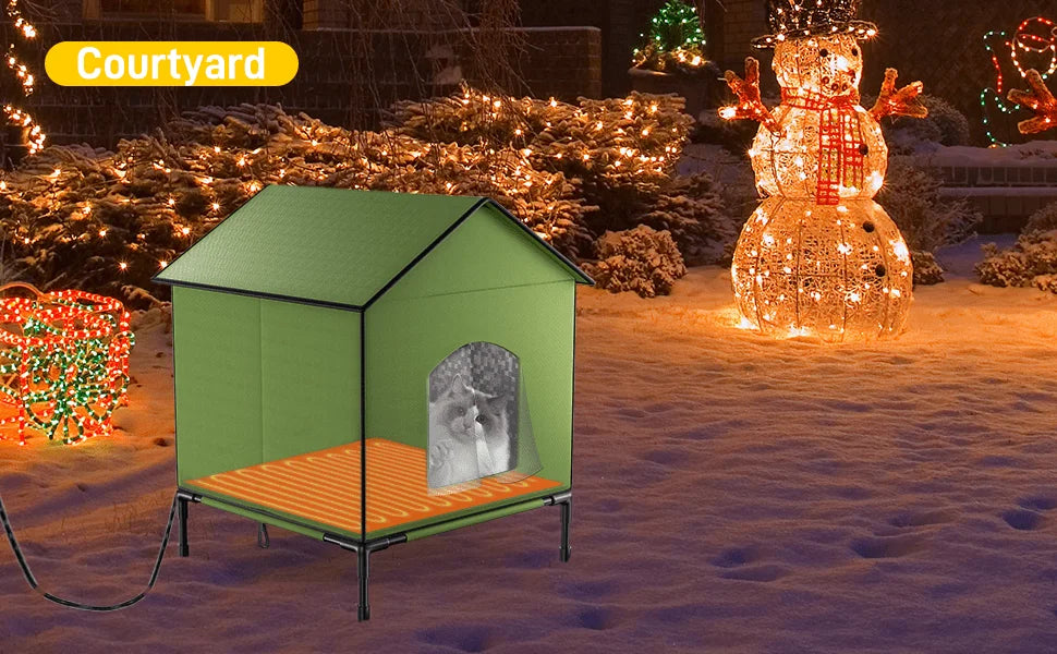 A heated outdoor house for cats set in a decorated snowy courtyard with Christmas lights.