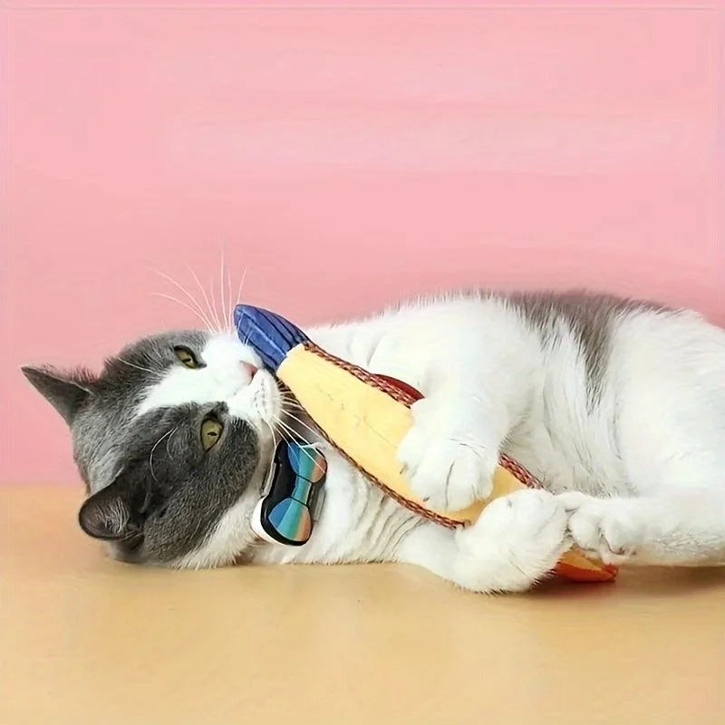 Grey and white cat enjoying a red and blue fishing toy for cats against a pink backdrop.