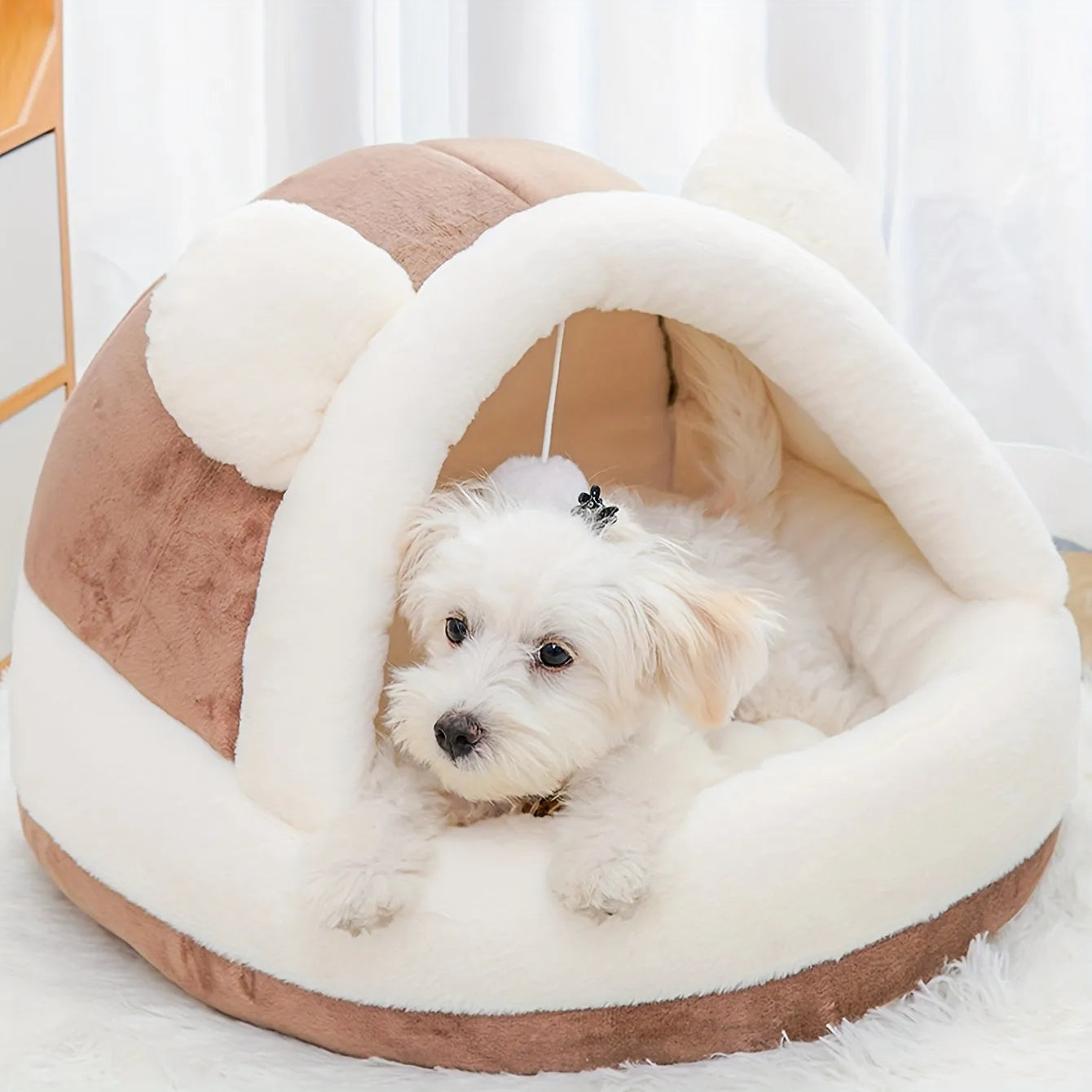 Plush brown dome-shaped best rated cat bed with a soft white lining and a dangling toy for added pet comfort and entertainment