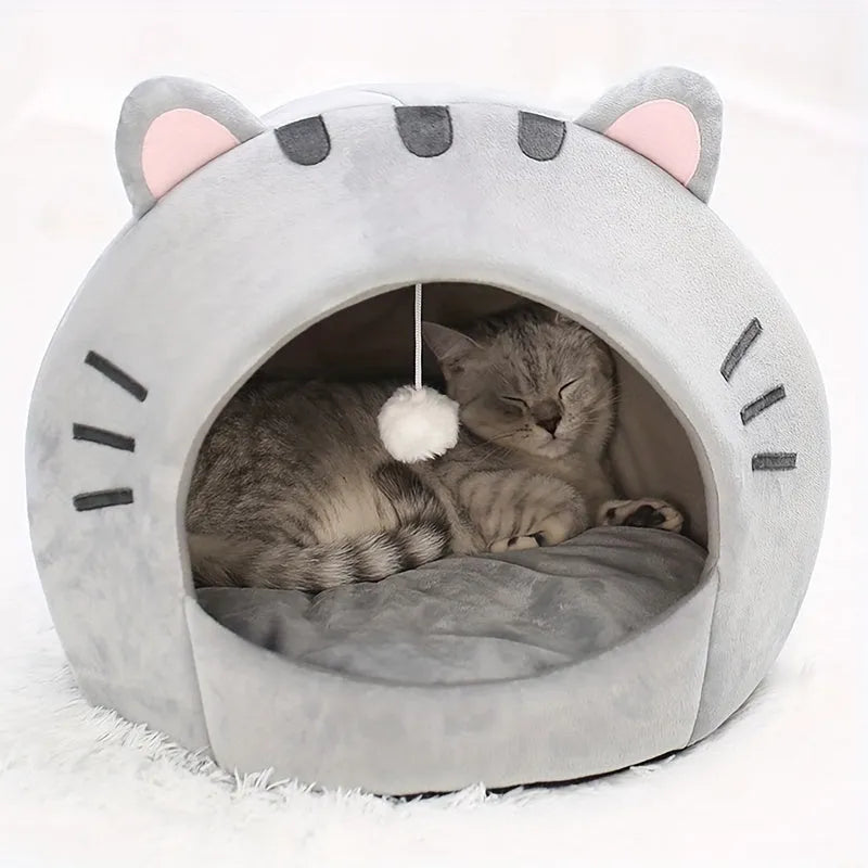 Cat sleeping comfortably inside a cozy gray cat bed warmer with adorable ear design and a hanging plush ball.