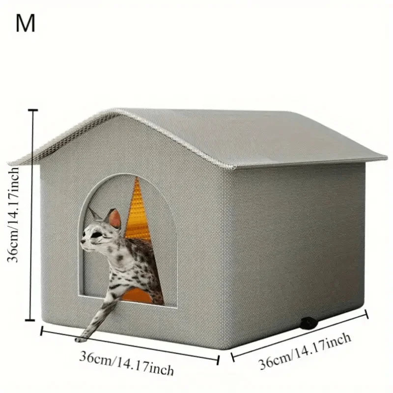 
A small gray cat house with a triangular roof and a front window opening. A cat is poking its head and paw through the window.