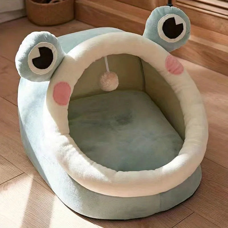 A green frog-shaped covered cat bed, designed with a spacious interior and a hanging toy for cats.