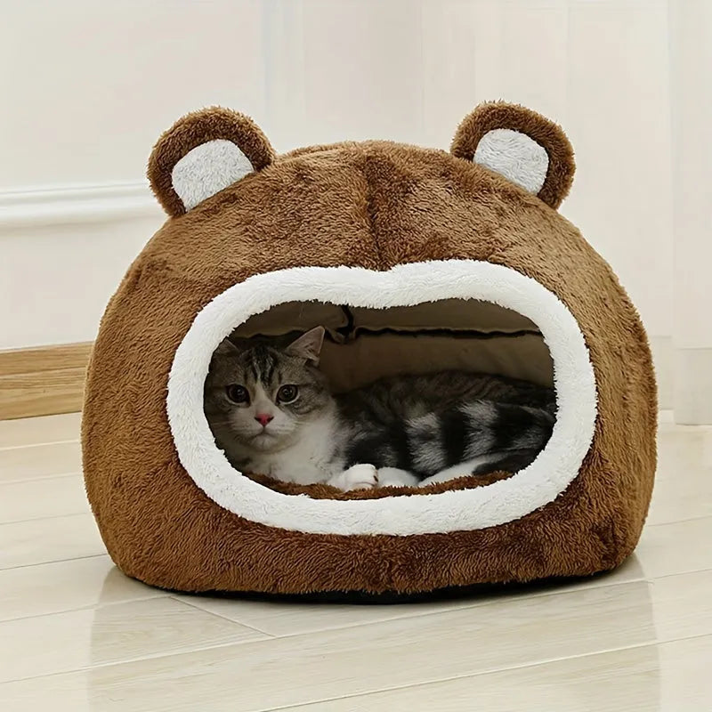 A cat resting inside a warm, bear-shaped cat bed with soft plush lining