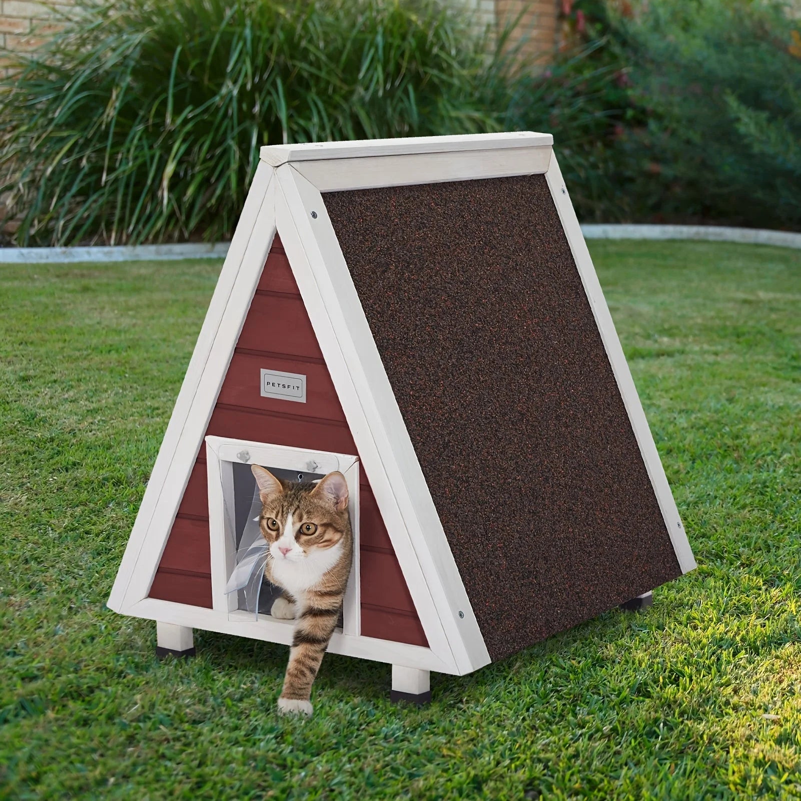 A small outdoor cat house with a transparent flap door, showcasing a cozy interior with a cat visible inside