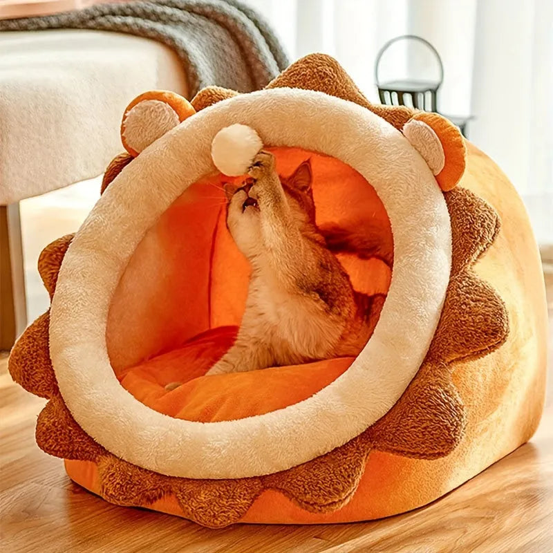 Cat playing with a hanging toy inside a lion-themed heated cat bed.