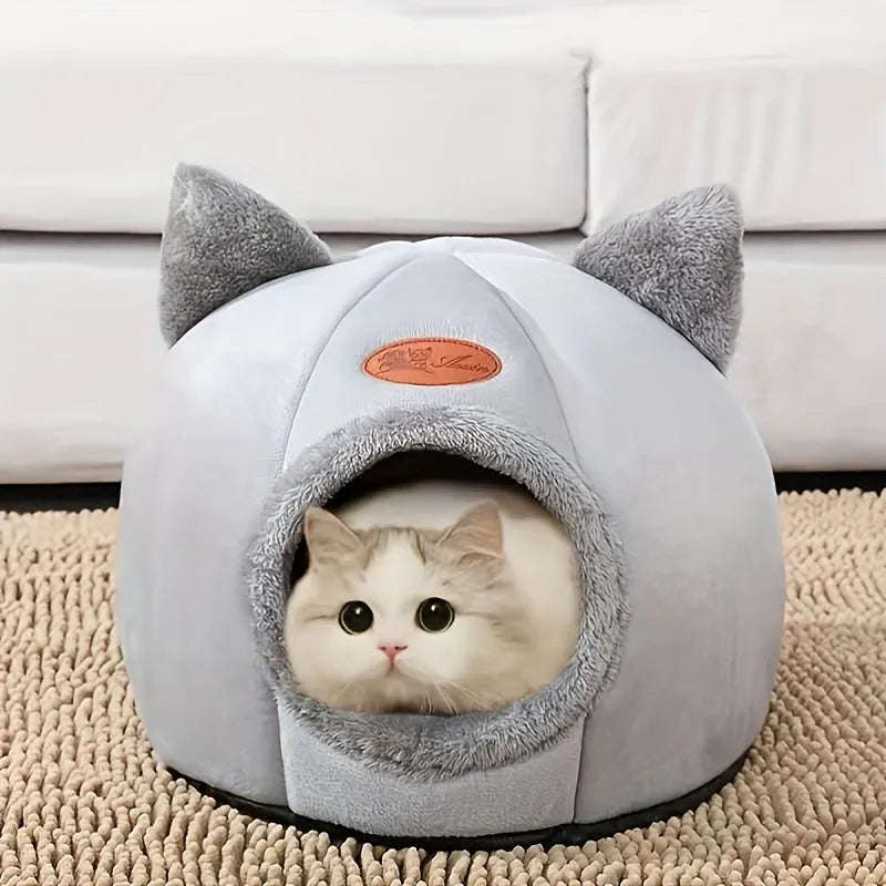 A fluffy white cat resting inside a cozy indoor heated cat bed shaped like a dome with ear accents.