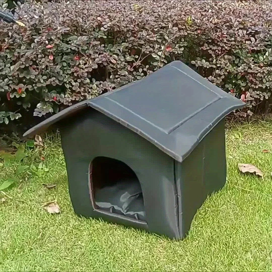 Outdoor shelter for stray cats with a curved roof, placed on a lawn near bushes, offering protection and comfort