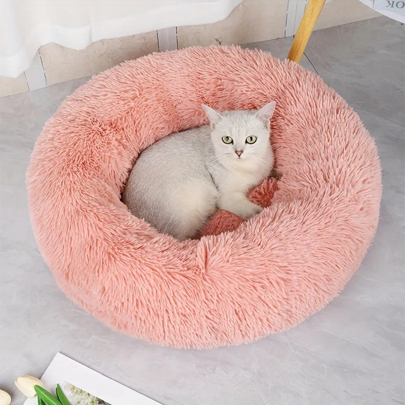 A white cat sitting in a soft pink fluffy cat bed, ideal for small pets to enjoy a warm and relaxing space. Cute Cat Beds in elegant colors.